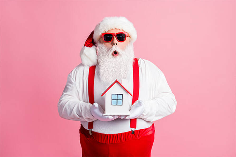 Santa holding a mini home. Selling your home during the holiday season.